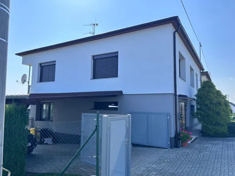 Moderní patrový dům s bílou fasádou a šedým přízemím