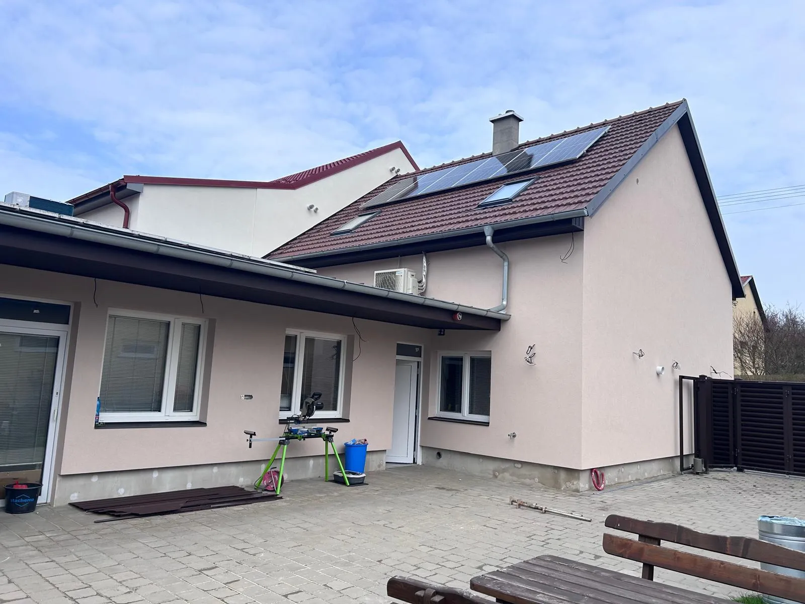 Dokončená přístavba se světlou fasádou a vydlážděným dvorem
